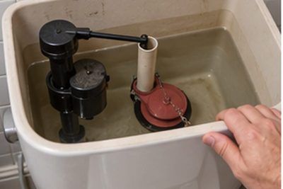 Open toilet cistern showing the fill valve and flapper during a repair in a Newark, Delaware bathroom