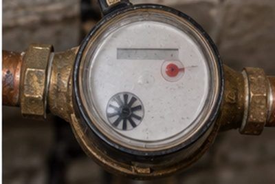 Residential water meter in a basement with the low-flow indicator dial visible